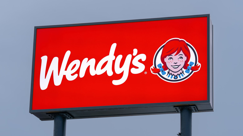 Wendy's restaurant neon-illuminated pylon sign against dusk blue sky,