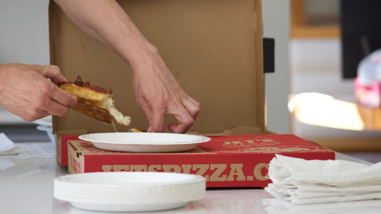 Hand reaching for Jet's Pizza from a takeout box