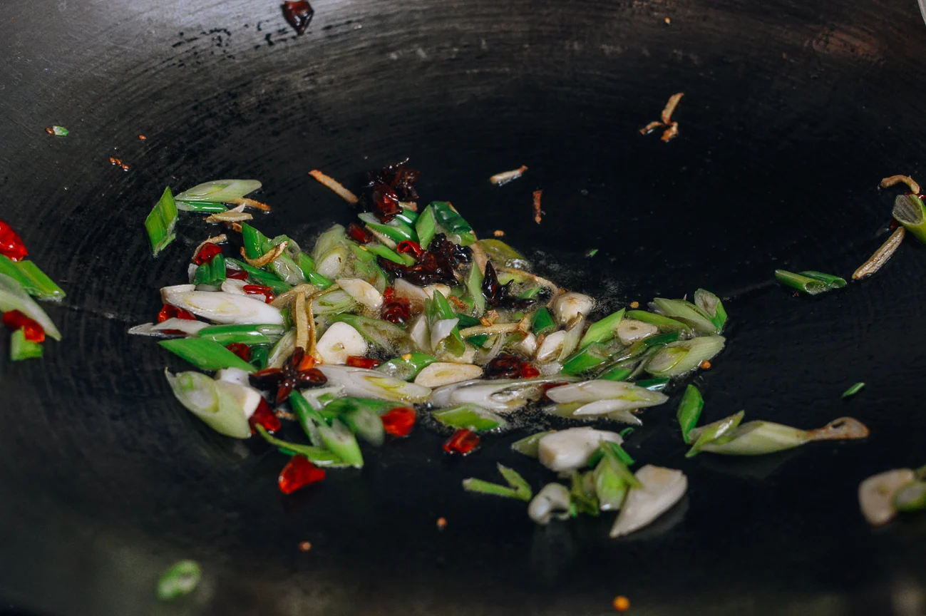 scallions, garlic, chilies, ginger, and star anise in wok