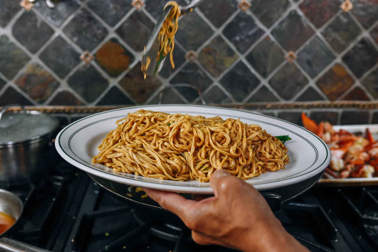 Transferring yee mein to serving plate
