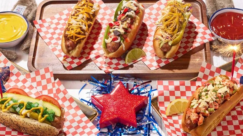 Five loaded hot dogs on red checked deli paper, with a red star on blue confetti in the front