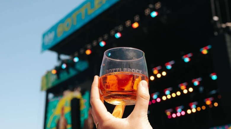 A person holding up win in a branded BottleRock glass with the blurred stage in the background