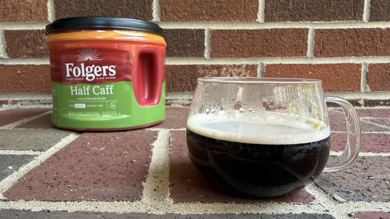 Plastic canister of half-caff ground coffee against brick wall