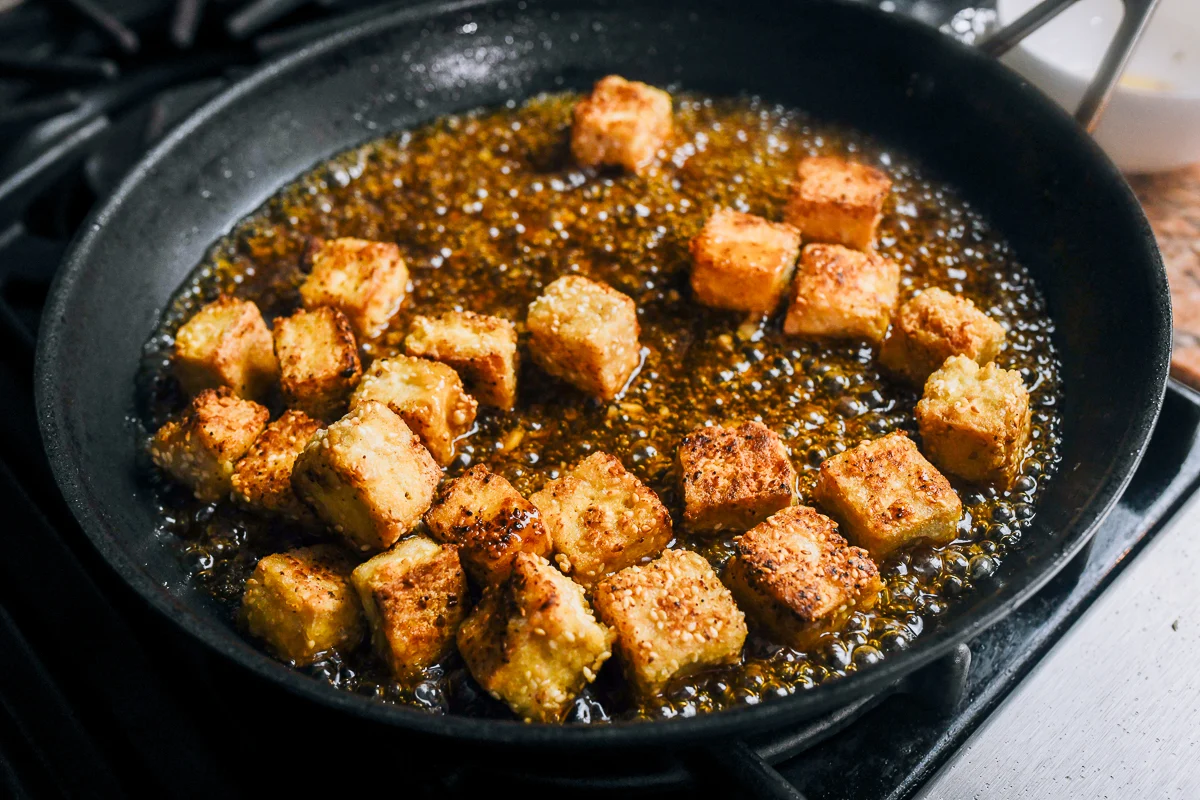 tossing crispy tofu in sauce