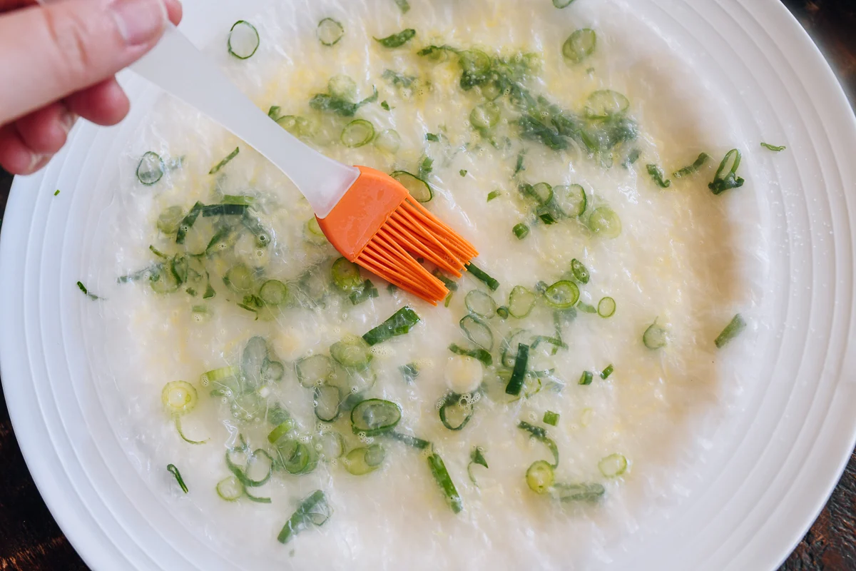lightly brushing gluten-free scallion pancake with egg