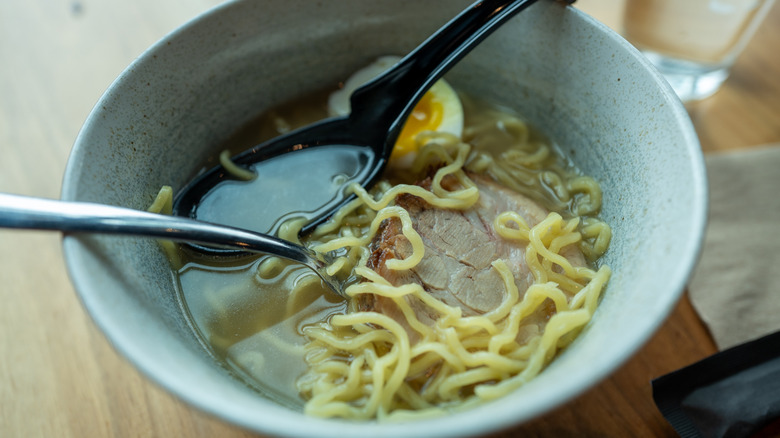 Bowl of ramen with spoons on a wooden table