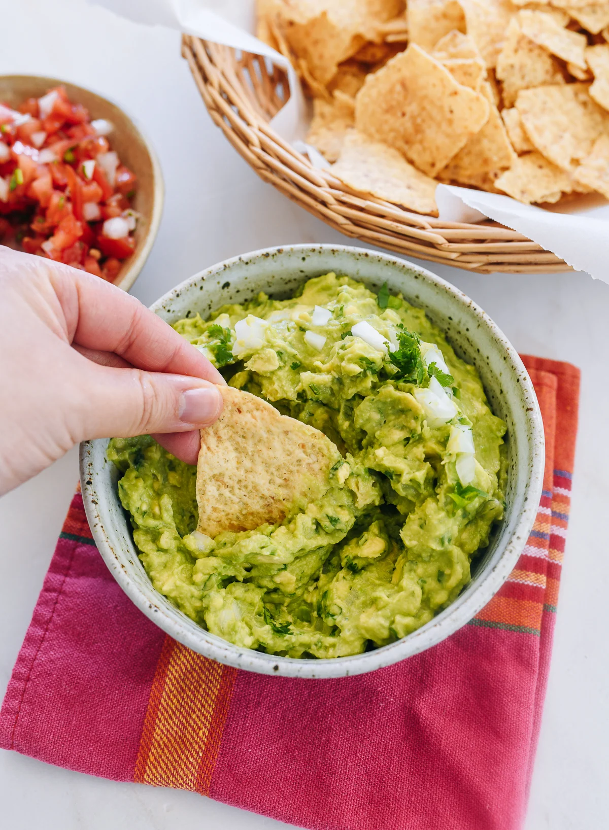 dipping tortilla chip into guacamole