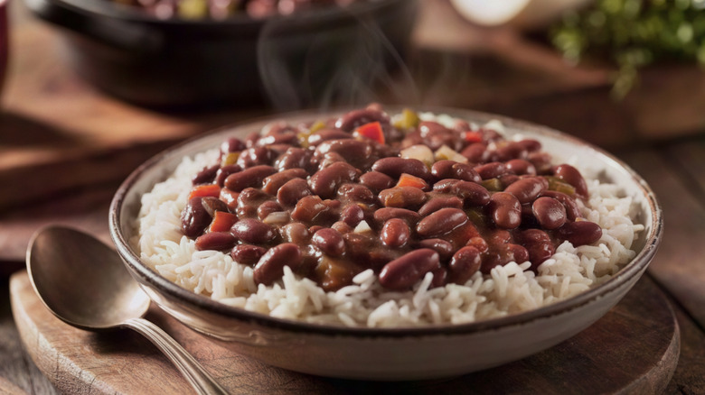 A wide bowl of white rice topped with cooked beans and vegetables.