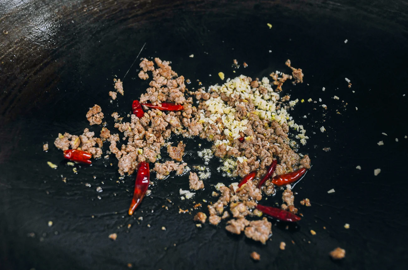 stir-frying chilies, garlic, ground pork