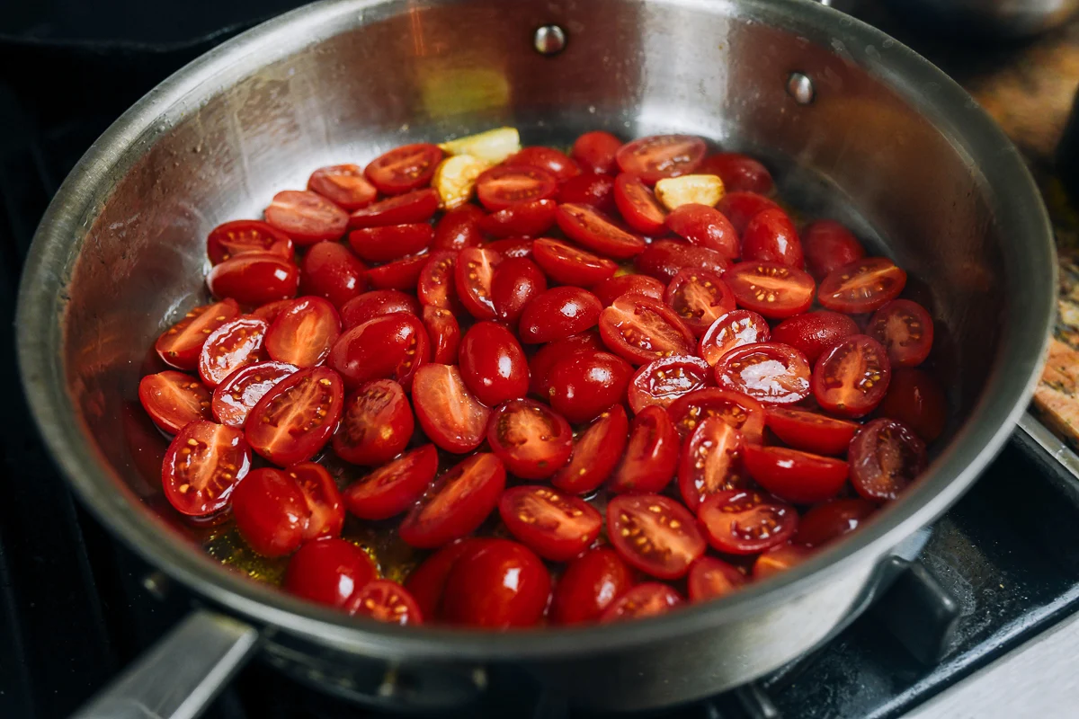 grape tomatoes added to garlic and olive oil in skillet