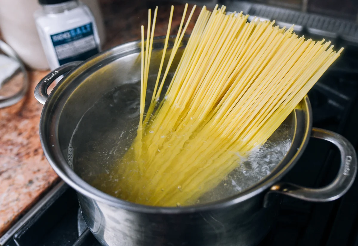 adding spaghetti to pot of boiling water