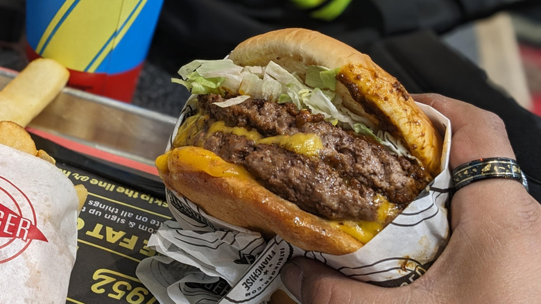Someone holding a chili cheeseburger from Fatburger.