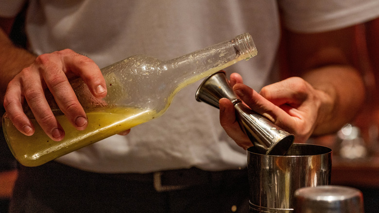 Man pours bottled juice into cocktail shaker