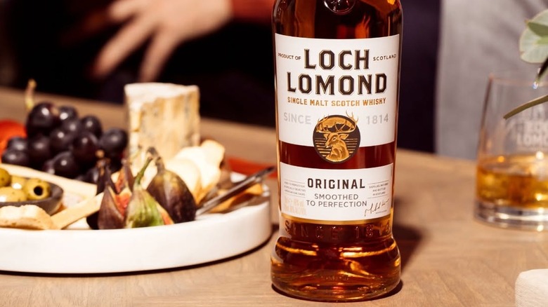 A bottle of Loch Lomond Original with food and a filled glass