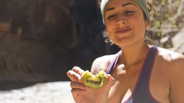 healthy woman hiking and eating kiwi
