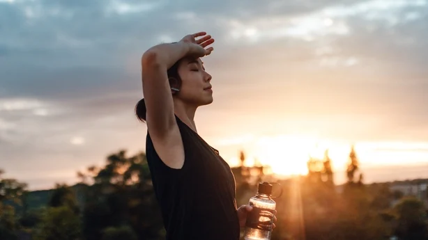 Young woman drinking water, exhausted after the daily training
