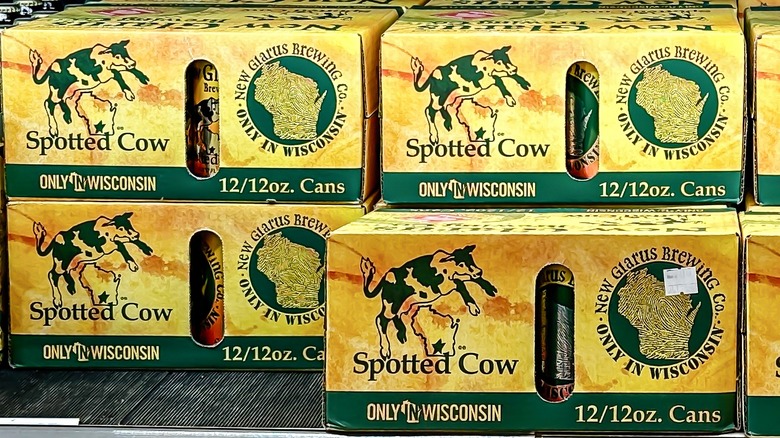 Several 12 can packs of Spotted Cow stacked together