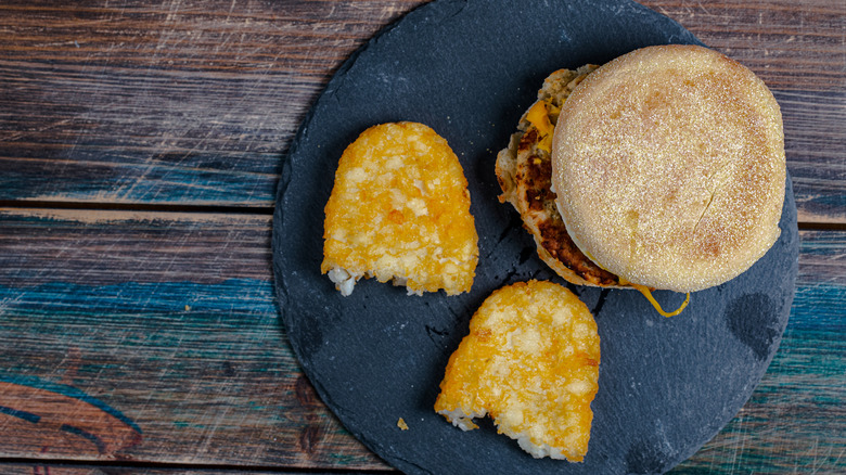 A blue plate with a McDonald's breakfast sandwich and hash browns
