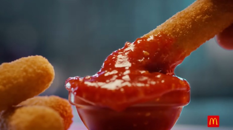 Mozzarella stick being dunked in sauce