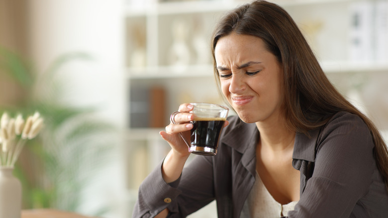 woman looking disgusting holding coffee