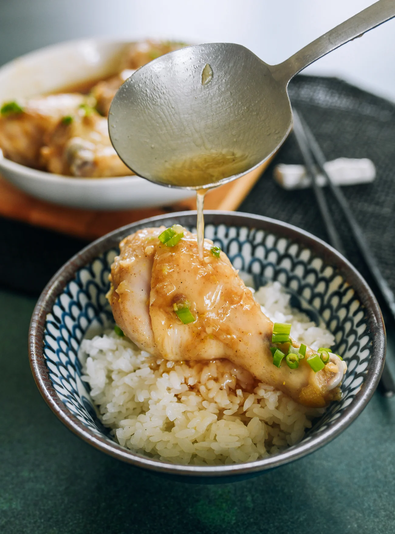 pouring juices onto steamed chicken leg over rice