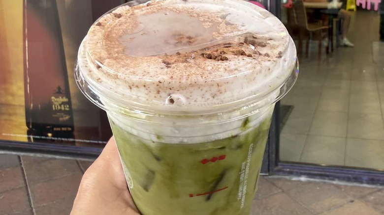 Hand holding cup of Dunkin' Tiramisu Marshmallow Matcha
