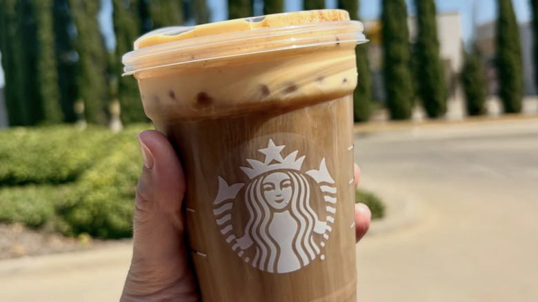 customer holding Starbucks pumpkin cream cold brew coffee drink