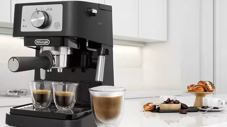 De'Longhi Stilosa espresso machine next to a cup of coffee and pastries
