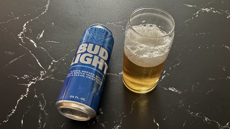 Bud Light can next to glass of beer on a black marble-like counter