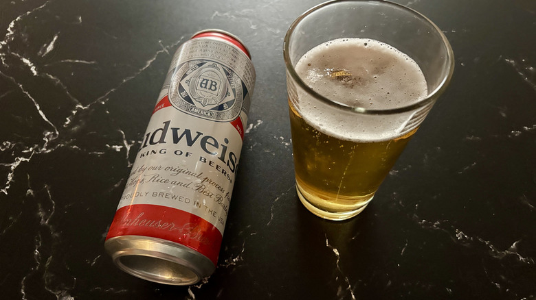 Budweiser can laying next to glass filled with that beer