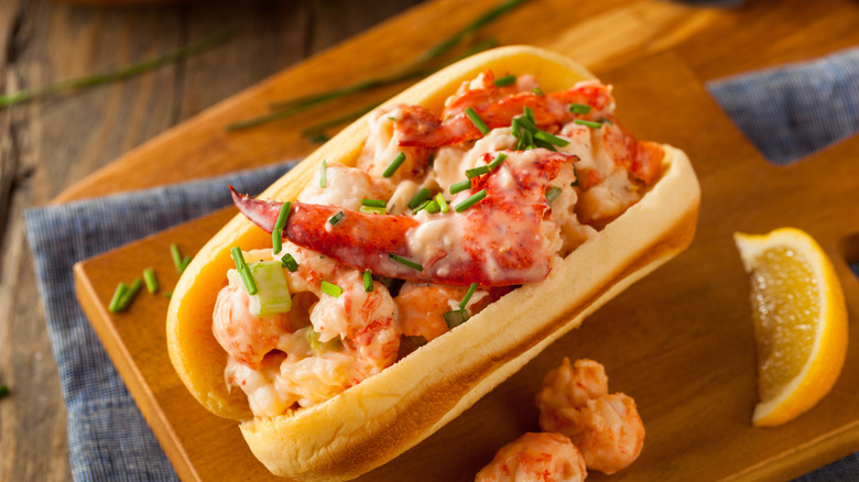 Seafood salad sandwich on a roll on top of a wooden cutting board