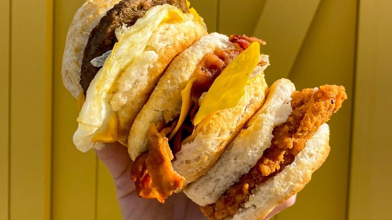 Someone holding several biscuit sandwiches from Biscuitville