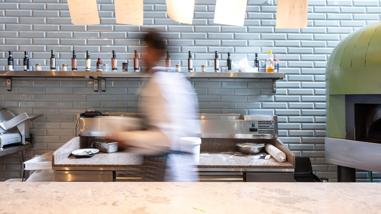 A blurry image of a chef hurrying in the kitchen.