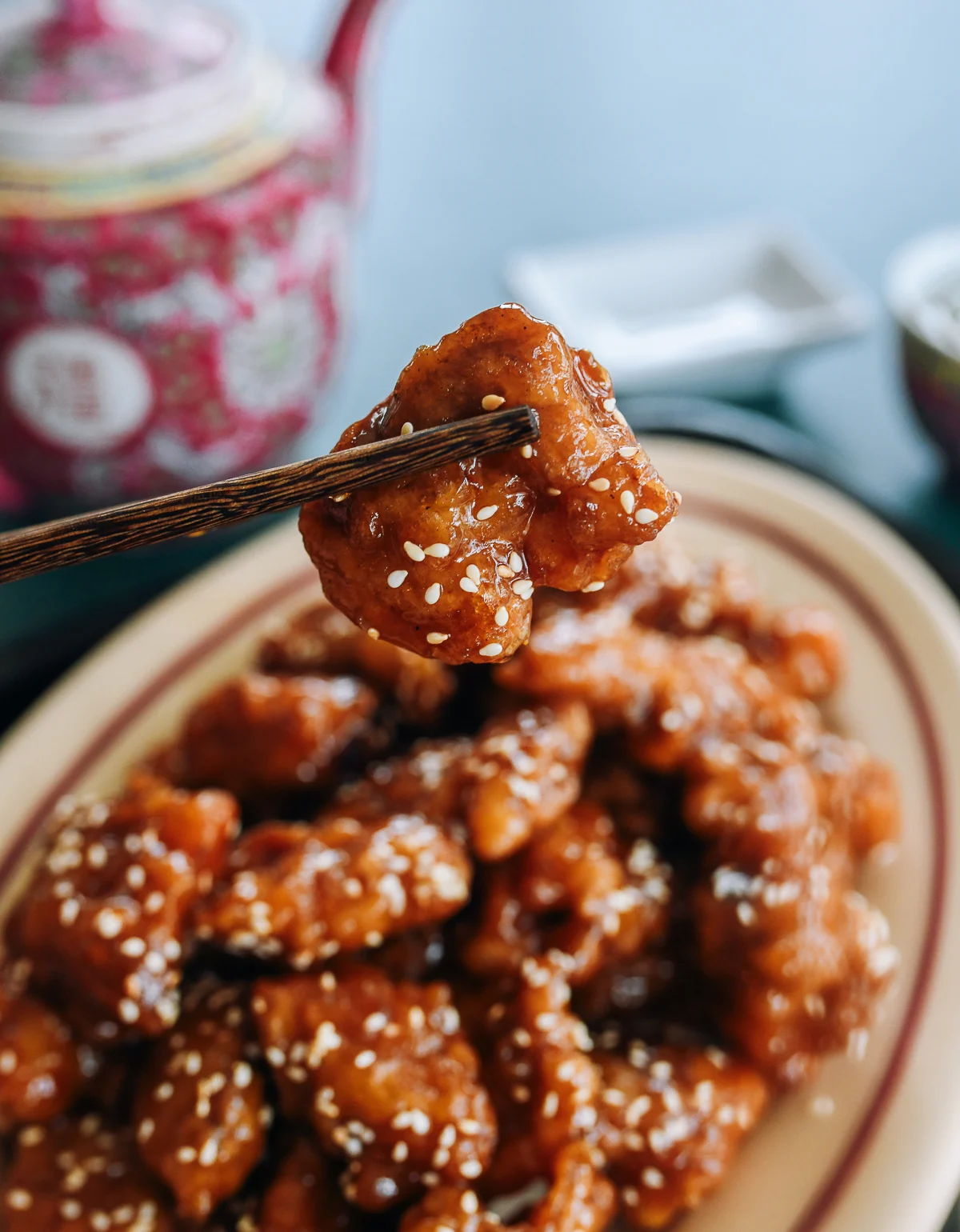 chopsticks picking up a piece of sesame chicken
