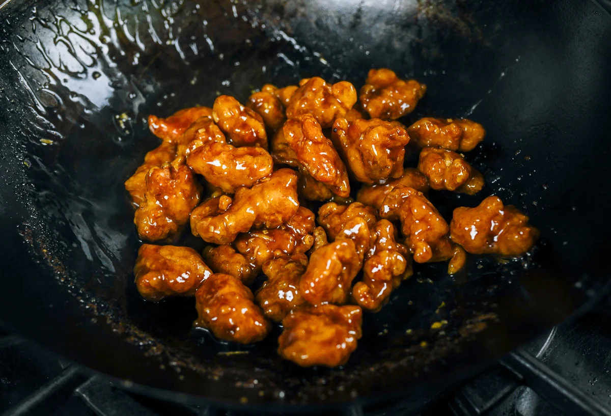 coating sesame chicken pieces in sauce