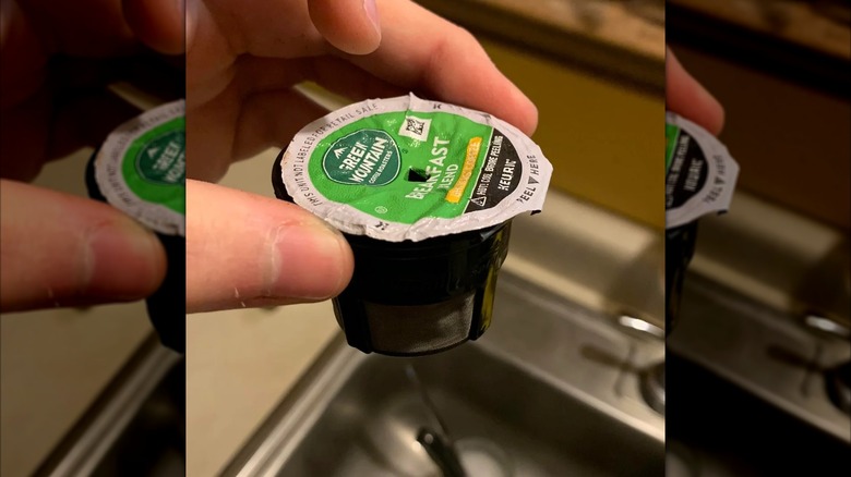 A hand holding a used Green Mountain Keurig Breakfast Blend coffee pod over a sink
