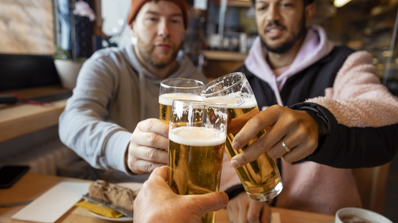 Table of three friends clinking pints of beer