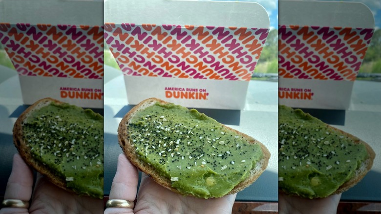 Hand holding slice of avocado toast from Dunkin'