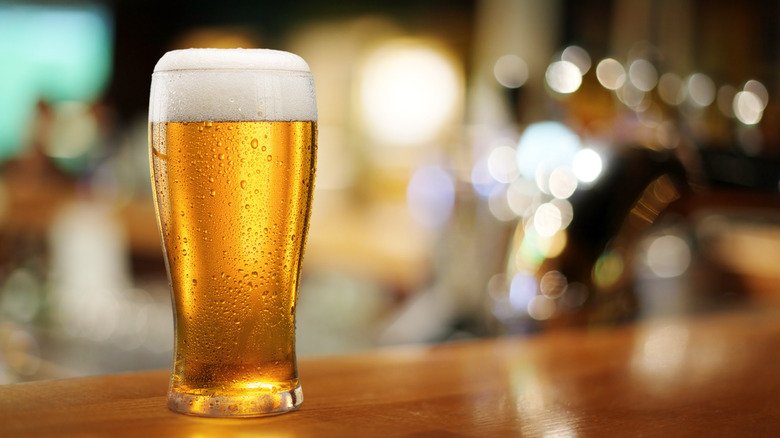 Foamy glass of beer on table with blurred background