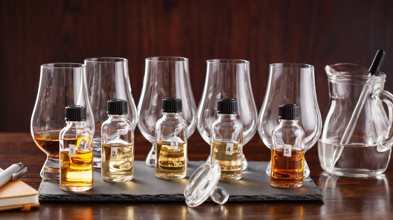 A whiskey tasting set up show with glasses, small whiskey bottles and a water jug with dropper
