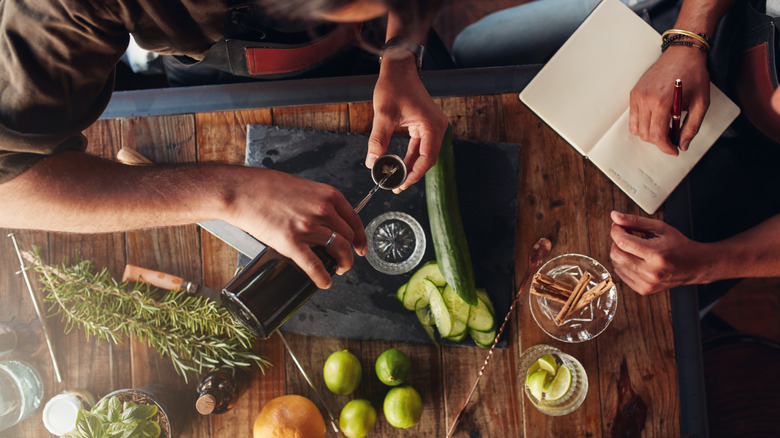 A top down shot of two people creating cocktails with a range of ingredients