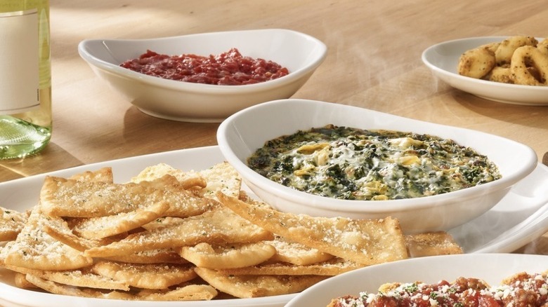 Bowl of Olive Garden Spinach-Artichoke Dip plated with crispy chips