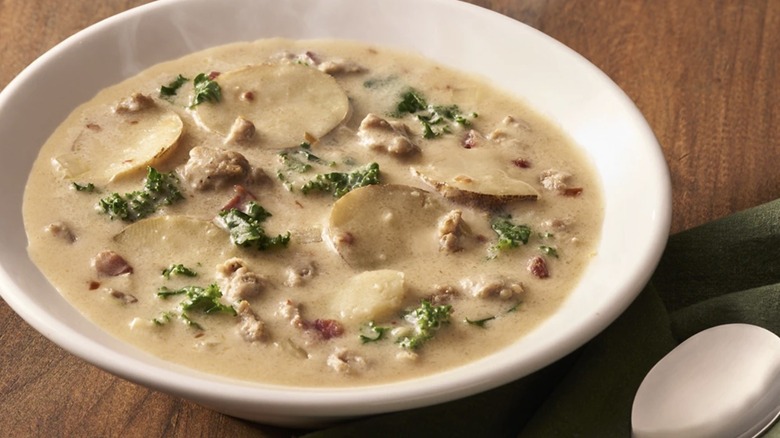 Bowl of Zuppa Toscana with kale, potato, and sausage floating in a creamy broth