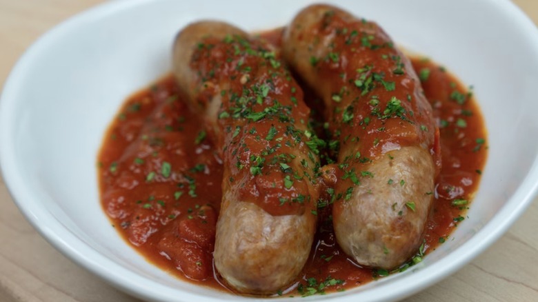 Pair of Olive Garden sausage links coated in marinara and dusted with herbs