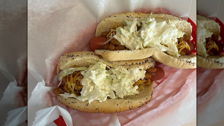 Two Vienna beef hot dogs with baked beans and coleslaw on paper in basket