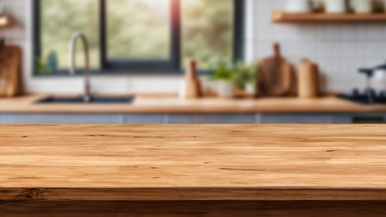 Close-up of a wooden countertop, behind a blurry kitchen space