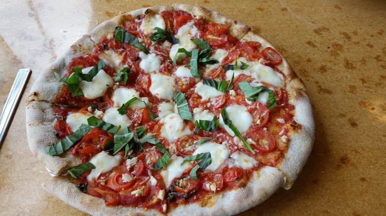 A Margherita pizza with mozzarella and tomatoes on a wooden table
