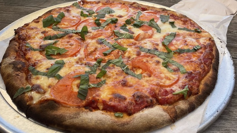 A margherita pizza on a steel paddle