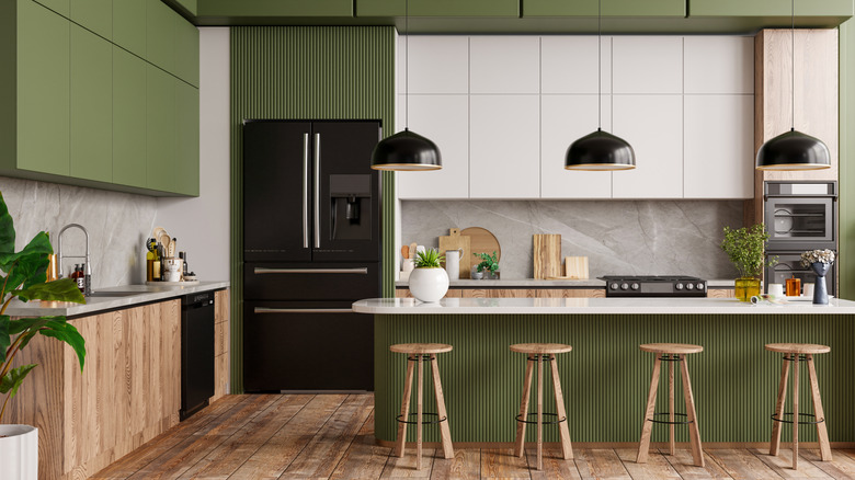 View of olive green kitchen with plants and wood chairs