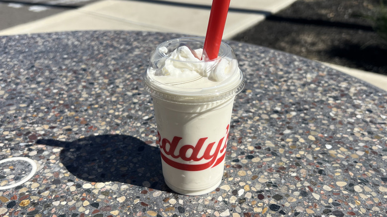 Freddy's Vanilla Shake with a straw on an outside table